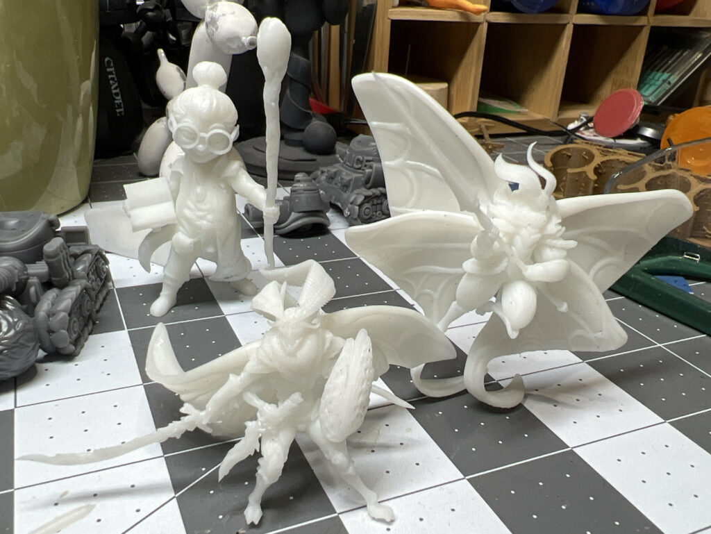 photograph of three miniatures; two mothfolk warriors, and a little girl wizard