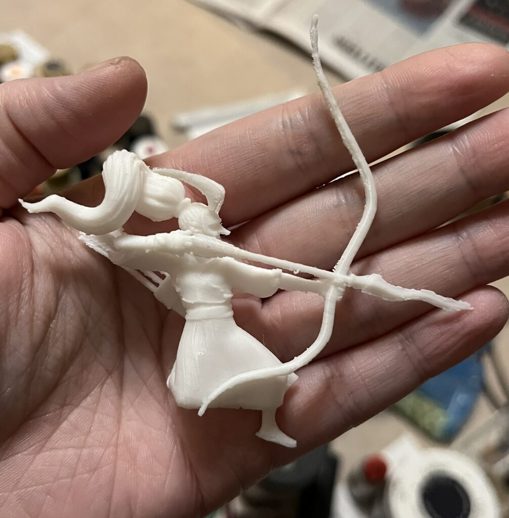 photograph of a 3d printed tengu archer figurine sitting in a person's palm