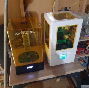 A small shelf with two 3d printers on it